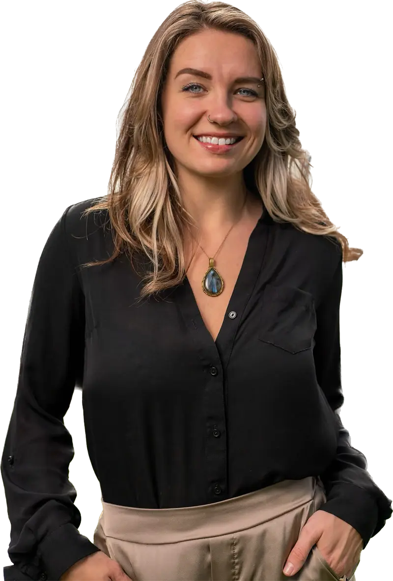 Smiling woman in a black blouse and beige trousers, wearing a teardrop pendant, isolated on white.